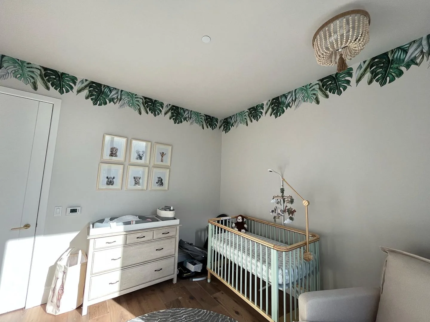 Animal kingdom themed nursery in Flatiron with crib, changing table and leaf decals