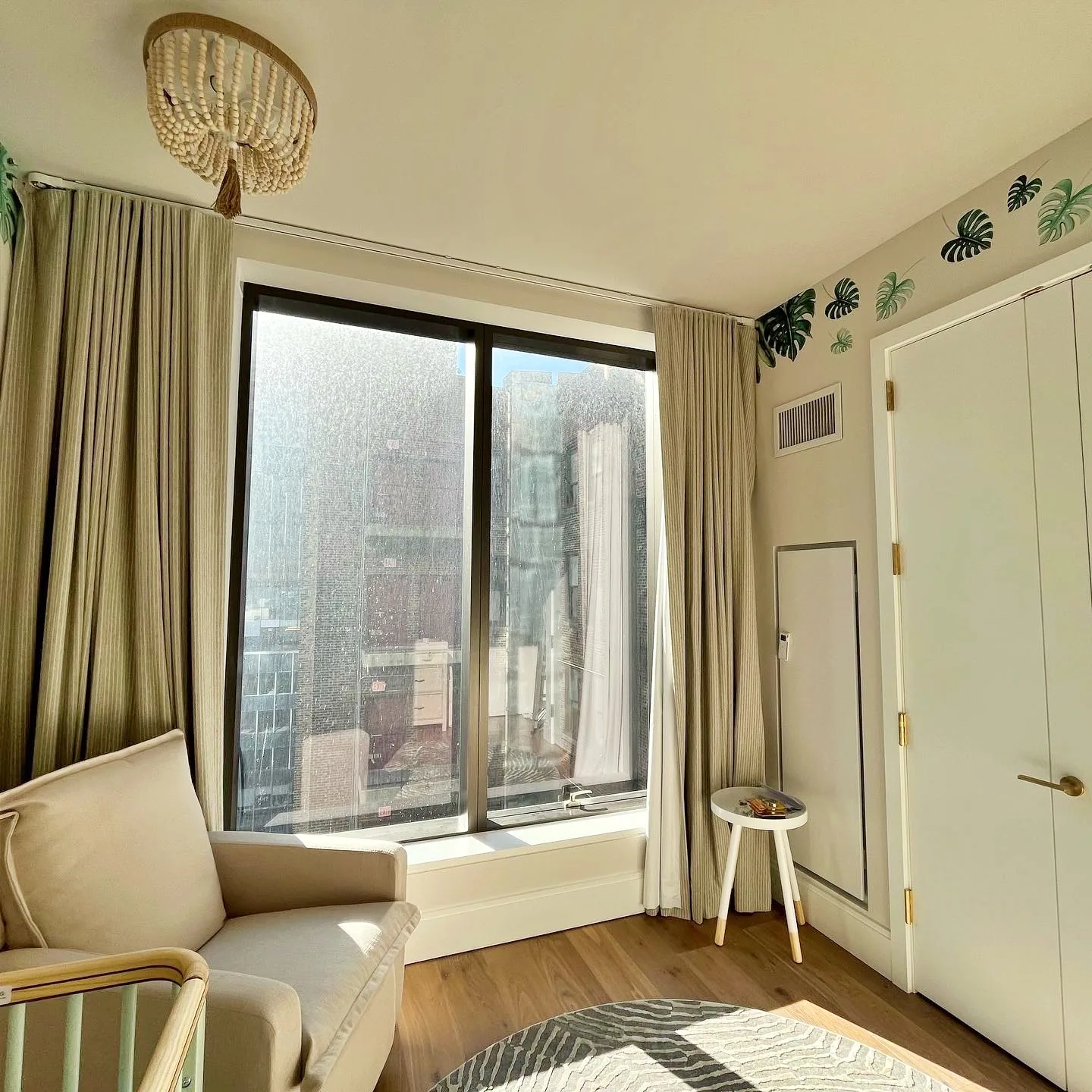 Nursery window wall with drapes, leaf decals and boho chandelier