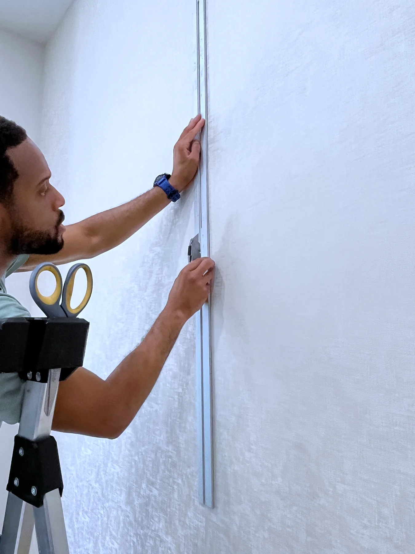 Julian Boyce leveling a wallpaper installation by hand