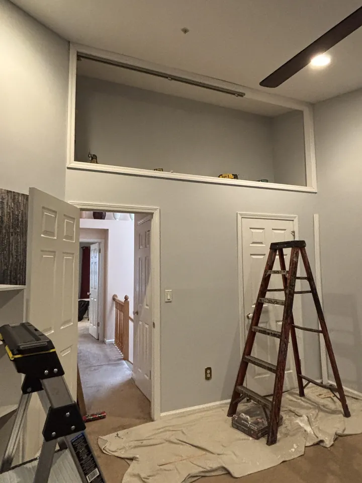 Painting preparation with ladder and drop cloths below the loft cavity