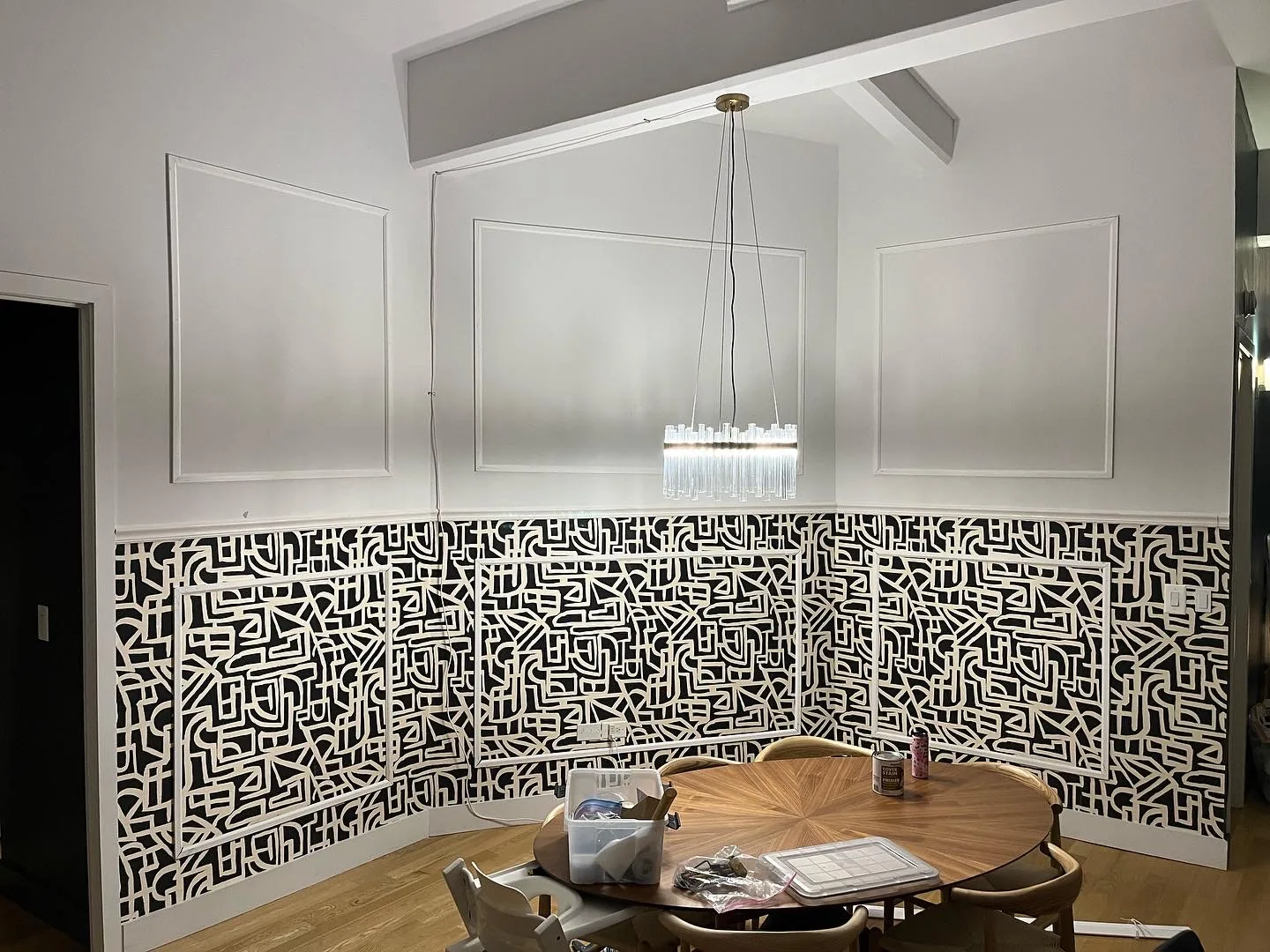 Bathroom vanity against black and white monogram wallpaper with sconce lighting