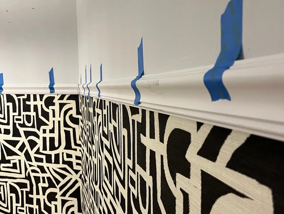Tribal monogram wallpaper being applied with painter’s tape guides