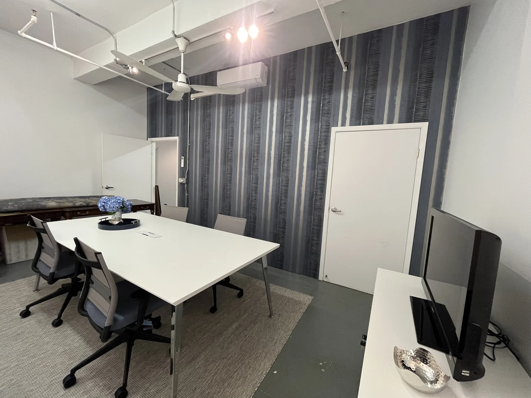 Mosaic NYC conference room with geometric wallpaper below the chair rail and white table