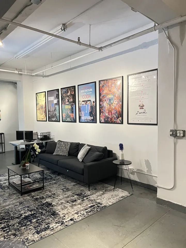 Mosaic NYC office lounge with charcoal sofa and framed art poster wall