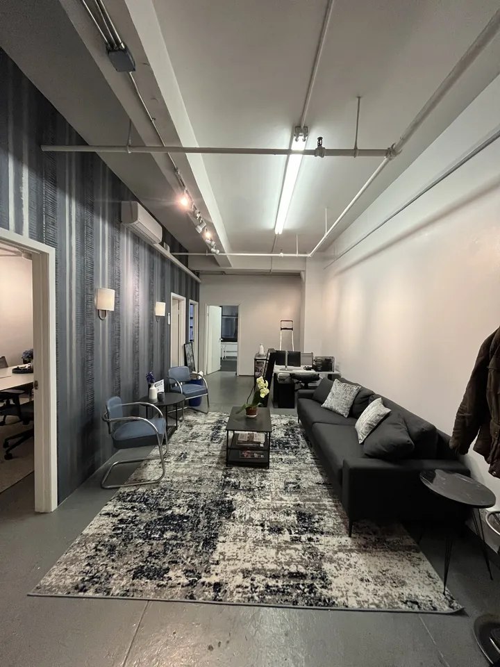 Corridor view of the Mosaic NYC lounge with area rug and charcoal sofas