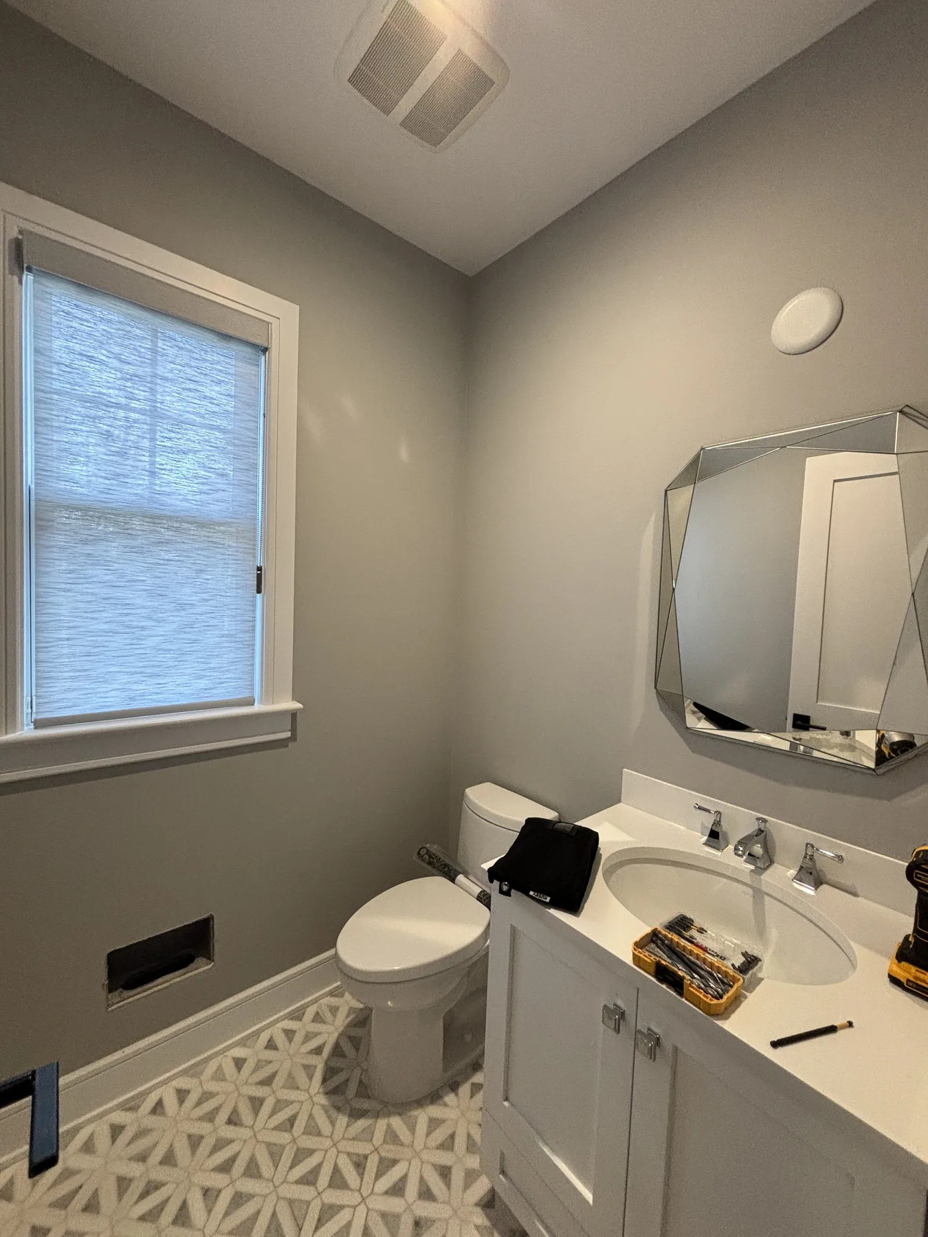 Powder room vanity angle with plain gray walls before wallpaper
