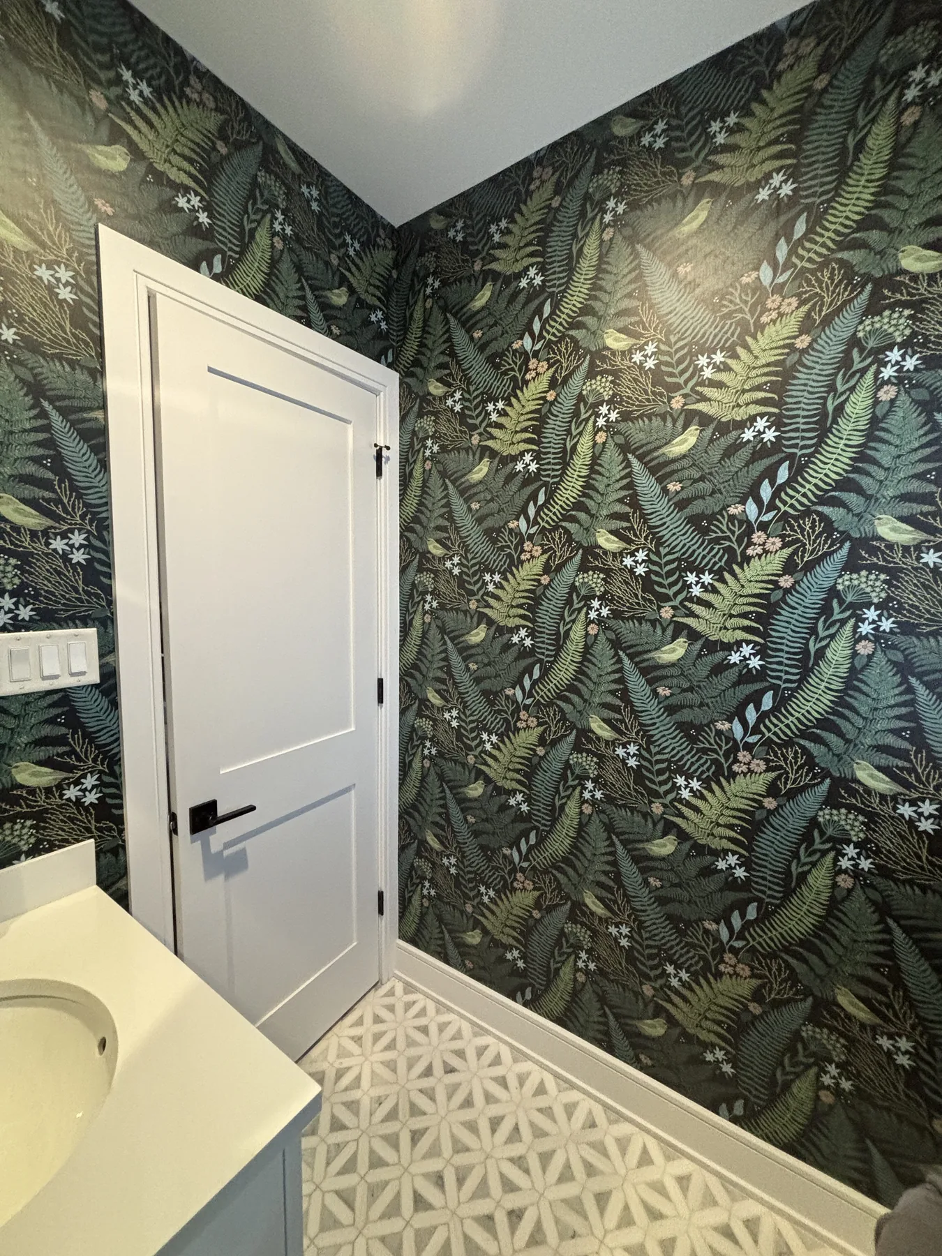 Powder room wrapped in dark fern wallpaper in Roslyn Heights, NY
