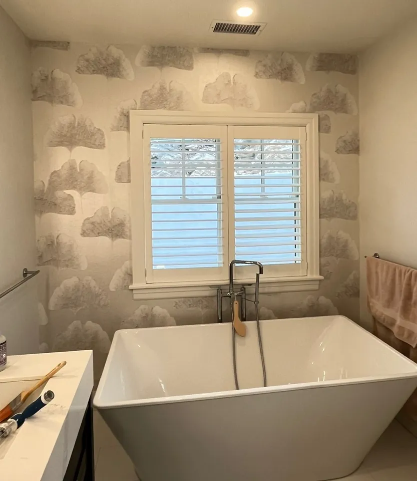 En suite bathroom window wall in cloud wallpaper with freestanding tub