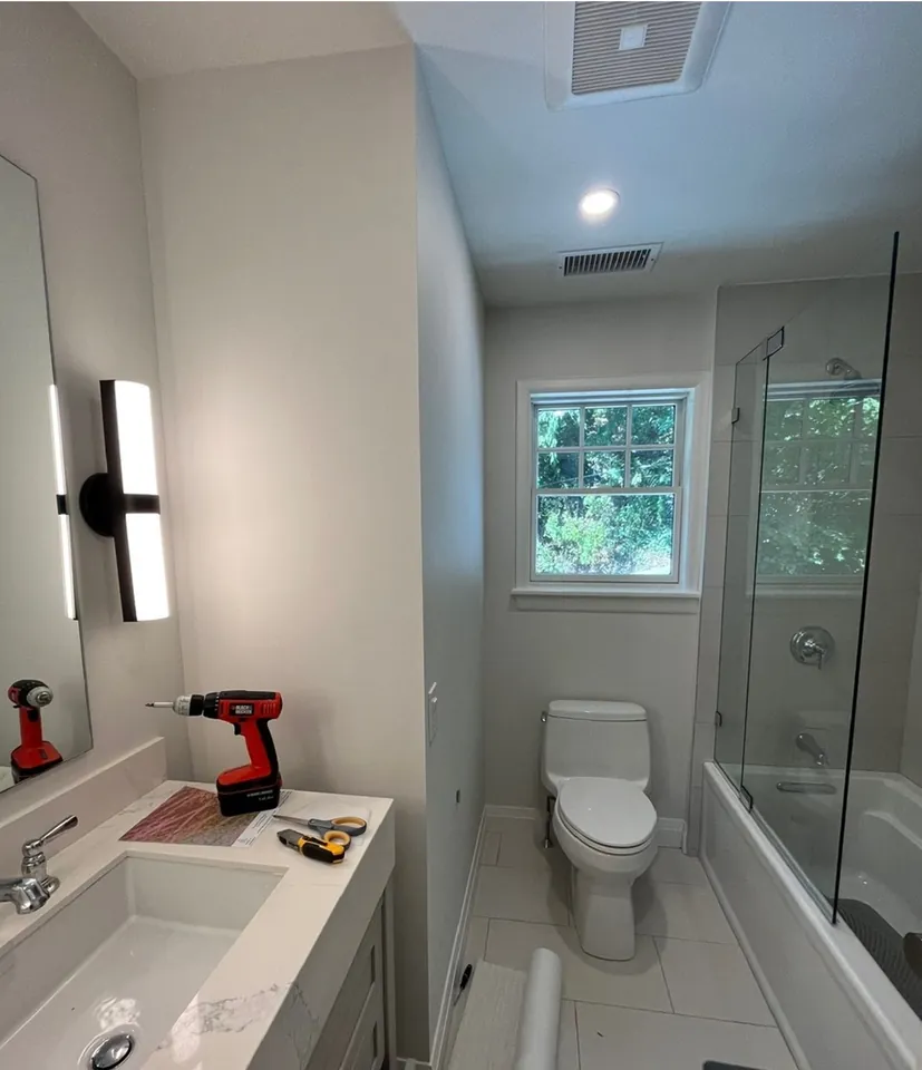 Grasscloth textured walls beside the glass shower enclosure