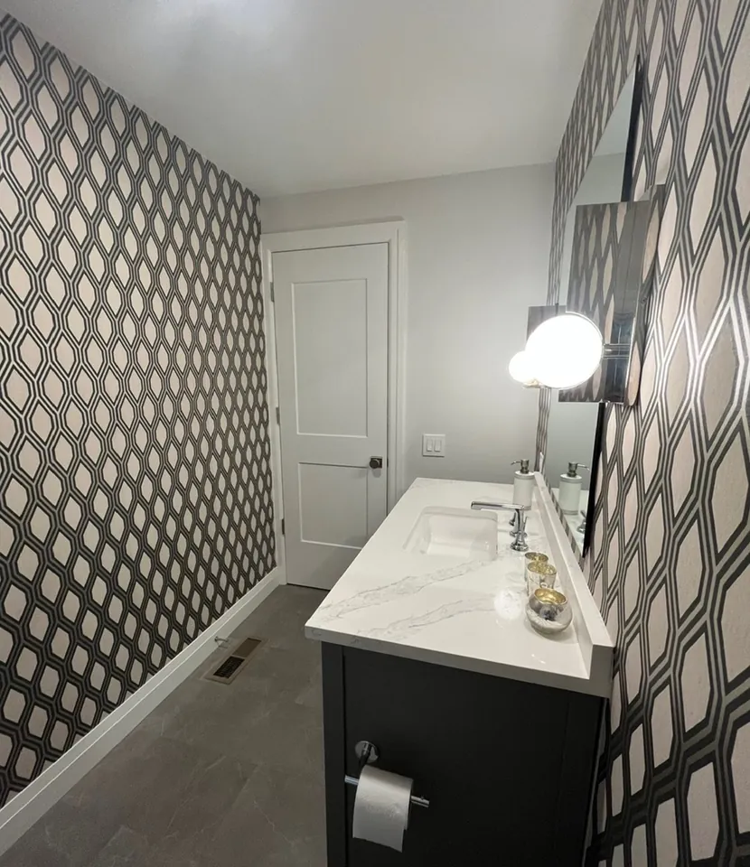 Powder room enveloped in matte diamond metallic monogram wallpaper